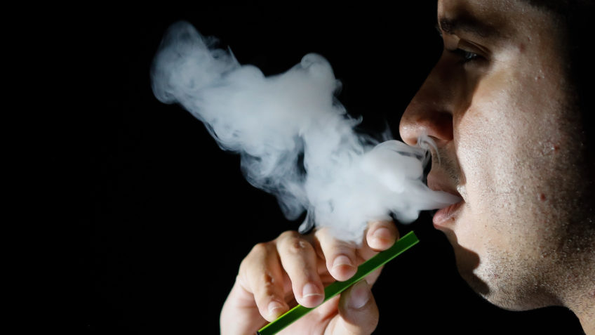 Homem soltando fumaça de um cigarro eletrônico